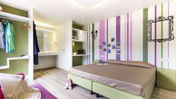 A bedroom with a bed, a wardrobe, a desk, and a mirror.