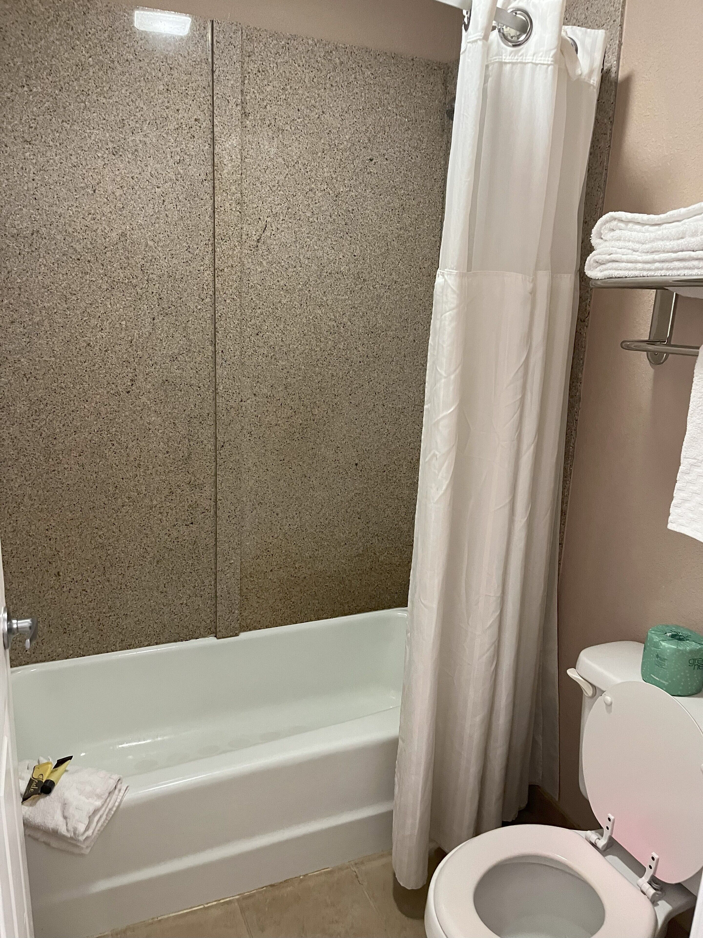 Un baño con bañera, inodoro y cortina de ducha.
