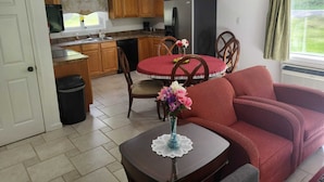 A compact living space with a dining table, a sofa, and a kitchen area including cabinets and appliances. - Pine Tree Inn (Parsons)