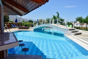 Una piscina al aire libre, sombrillas, sillones reclinables de piscina