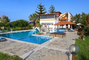 Una piscina al aire libre, sombrillas, sillones reclinables de piscina