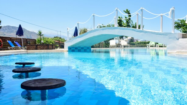 A swimming pool with a bridge, lounge chairs, and a mountainous backdrop. - Dias studios (Apokoronas)