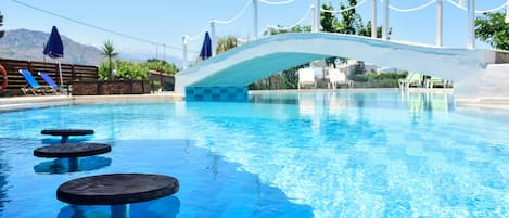 Una piscina al aire libre, sombrillas, sillones reclinables de piscina