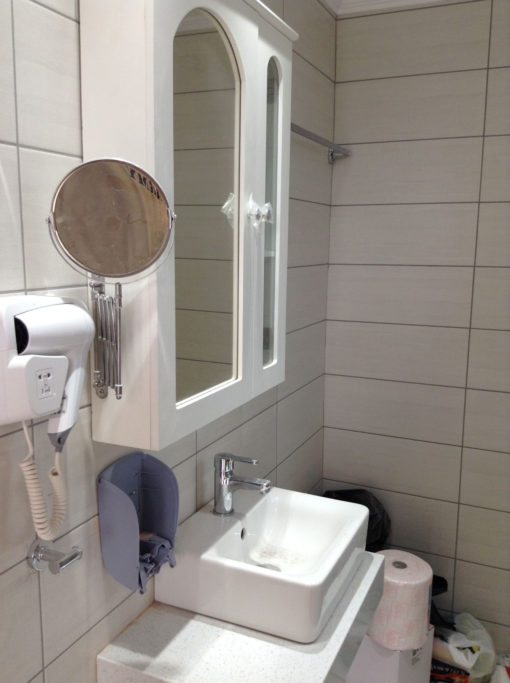 A bathroom with a sink, mirror, hairdryer, and towel rack.