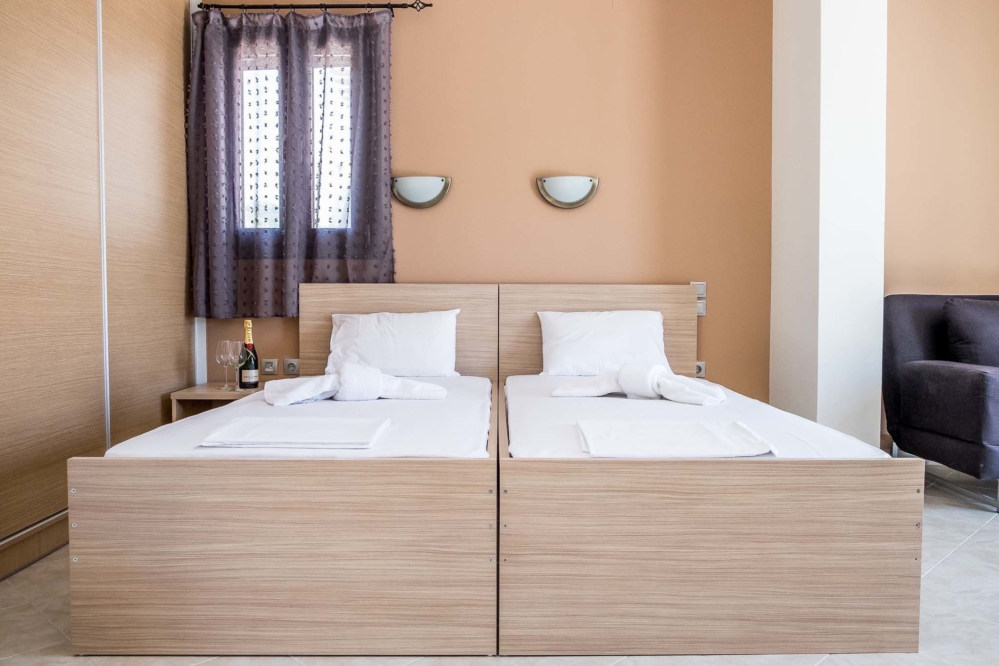 A double bed with a wooden frame, two bedside tables, a nightstand, a chair, and a window with curtains.
