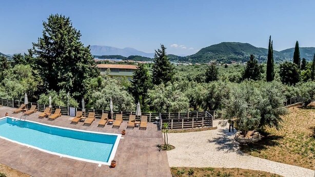 A pool area with lounge chairs, a wooden deck, and a view of mountains.
