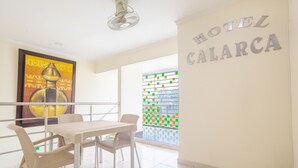 Une chambre d’hôtel dotée d’un coin repas comprenant une table et des chaises, un ventilateur de plafond et une grande fenêtre donnant sur l’extérieur.