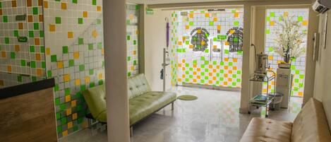 A reception area with a green sofa, a beige sofa, and a tiled wall with green, yellow, and white squares.