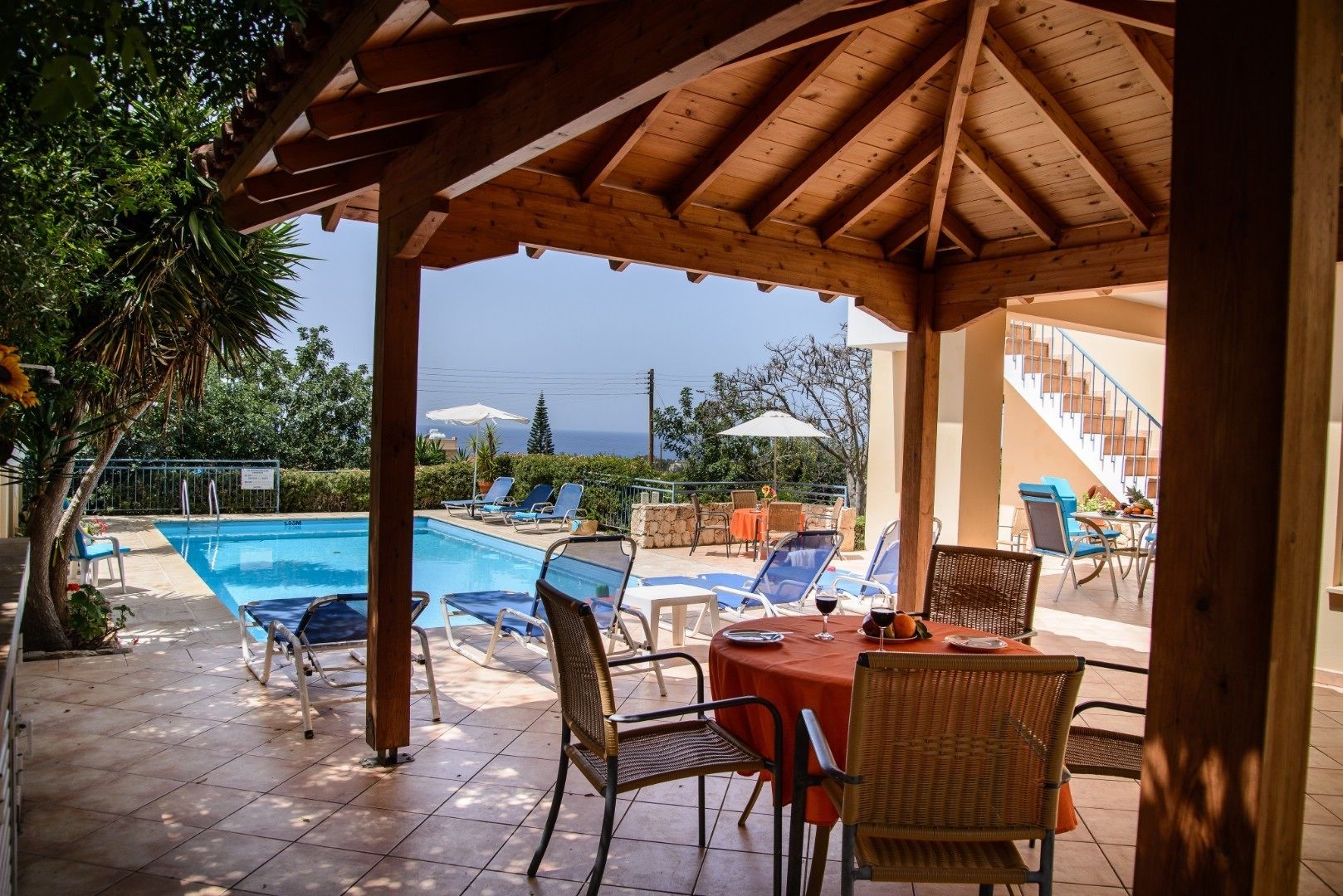A covered outdoor area with a pool, lounge chairs, and a table with drinks.