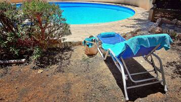 Relax by the serene pool surrounded by lush greenery and a shaded seating area.