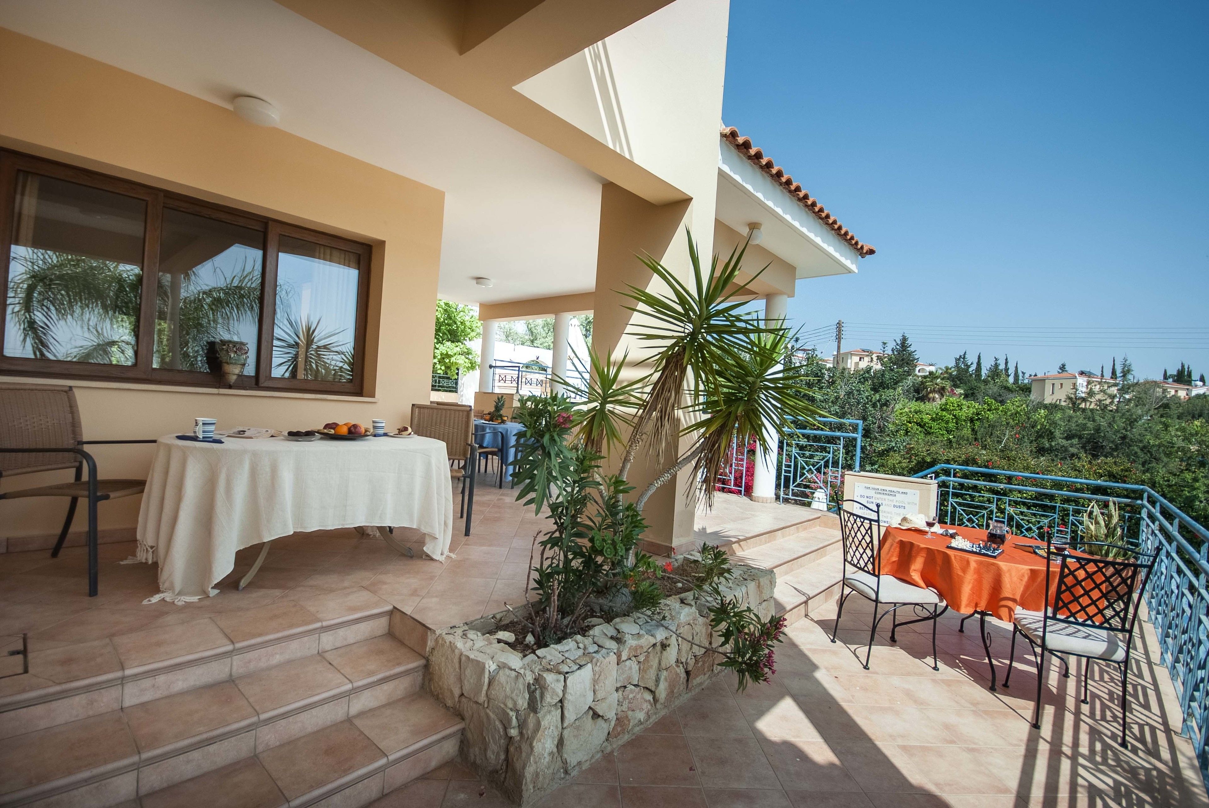 Una terraza con mesas al aire libre, una jardinera de piedra y vistas del paisaje circundante.
