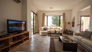 Uma sala de estar com televisão, sofás, mesa de centro e um aparador.