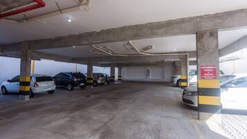 Garagem de estacionamento com vários níveis, pilares de concreto e colunas listradas em amarelo e preto.