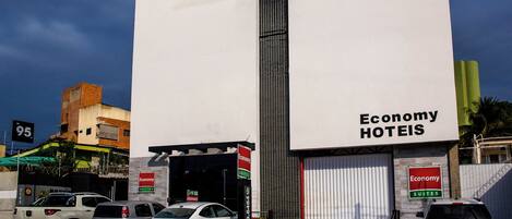 A hotel with a large sign reading 'Economy Hotels' and multiple cars parked in front.