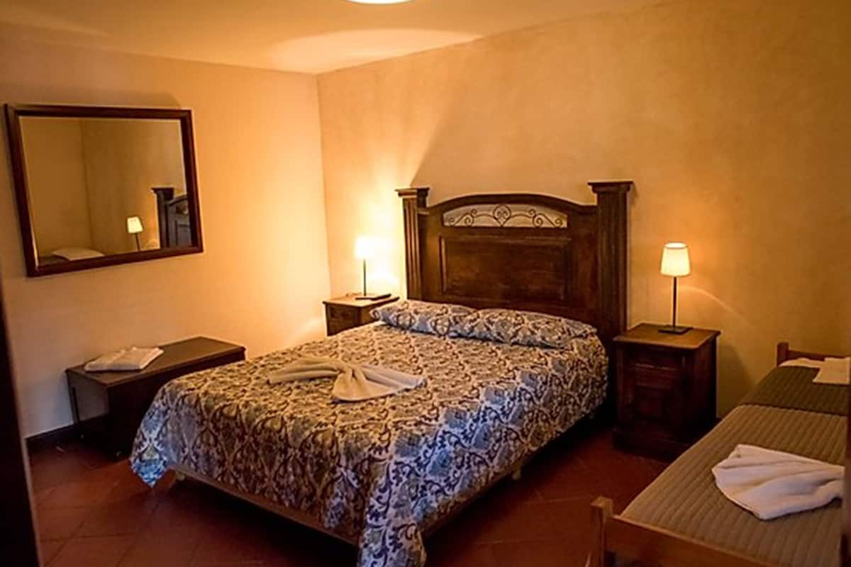 Ein Hotelzimmer mit Bett, Nachttisch, Stuhl, Schreibtisch und Spiegel.
