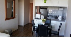 A compact kitchen with a dining area, a refrigerator, a microwave, and a small sink. - Departamento Los Lucumos (La Serena)