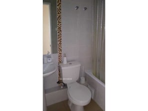 A bathroom with a toilet, sink, and shower curtain. - Departamento Los Lucumos (La Serena)
