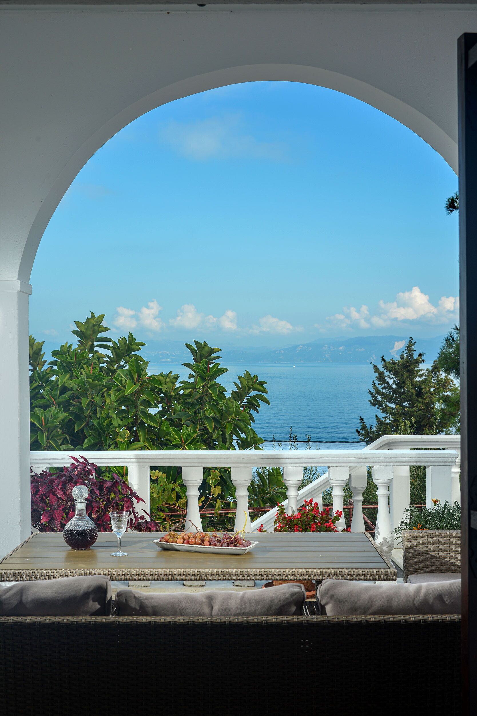 Ein Balkon mit Meerblick, weißen Geländern und einem Tisch mit Flasche und Glas.