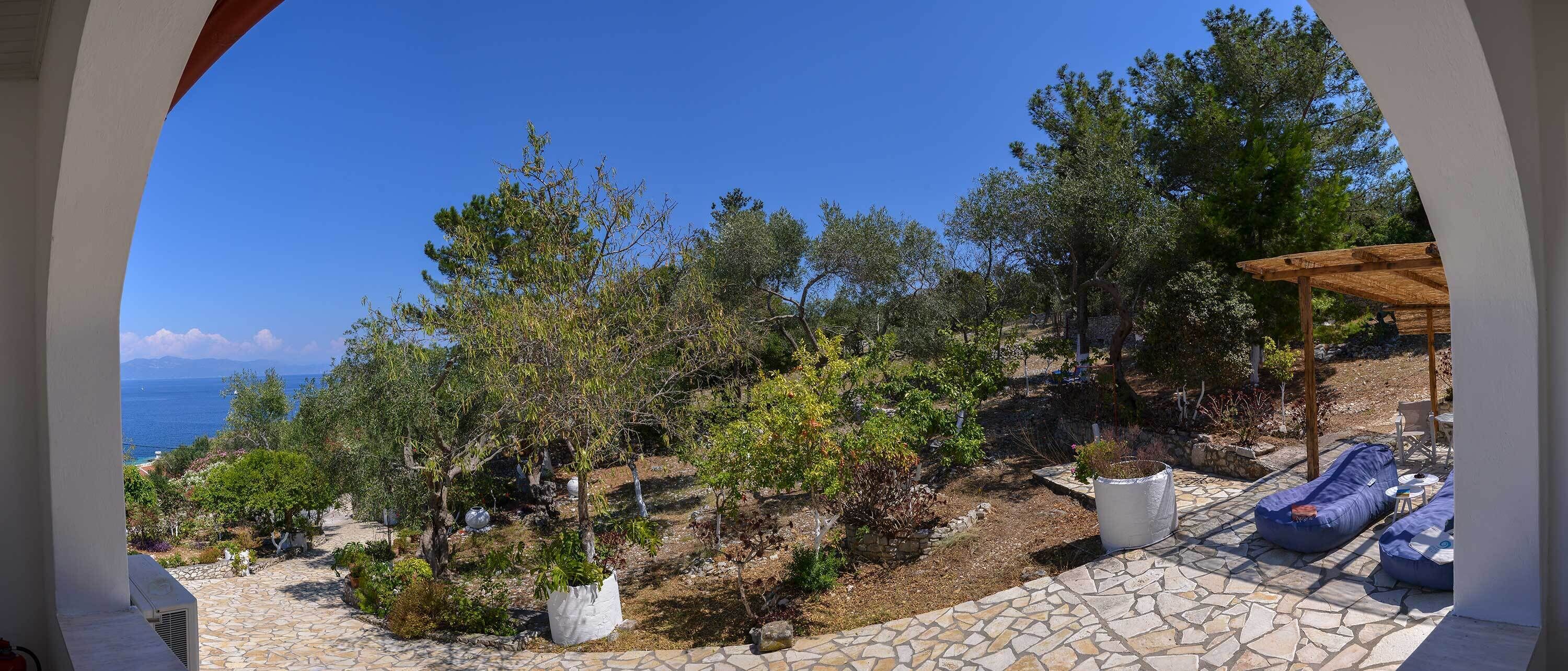 A stone patio with outdoor seating and a view of the sea.