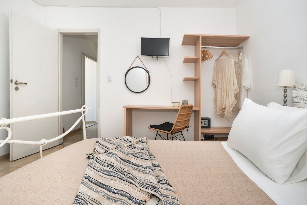 A bedroom with a bed, a desk, a chair, a TV, and a wardrobe.
