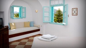 Een kamer met een bed, een bank, een tafeltje en een raam met uitzicht op een boom.