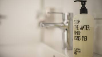 A bathroom with a white sink and a bottle of soap with a pump dispenser.