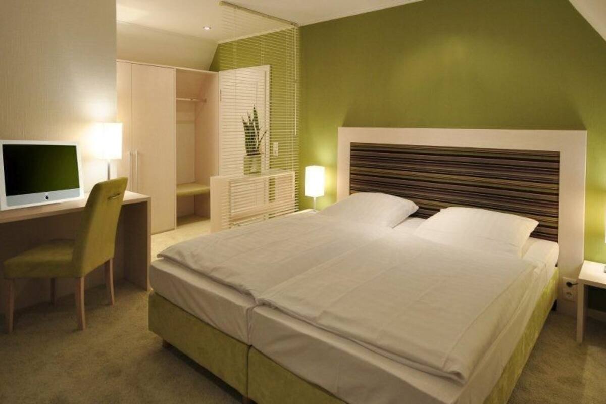Une chambre d’hôtel moderne avec un grand lit, un bureau équipé d’un ordinateur et une chaise.