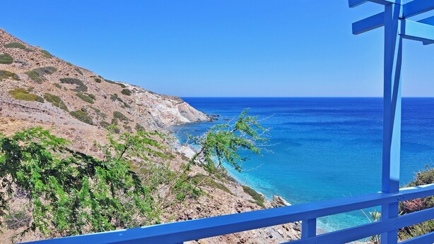 A coastal view with a rocky hillside and a clear blue sea. - Thalassopetra (Milos)