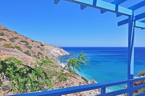 A coastal view with a rocky hillside and a clear blue sea. - Thalassopetra (Milos)