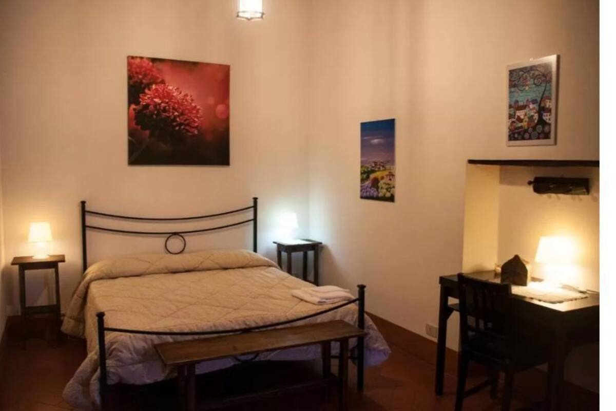A bedroom with a bed, bedside tables, and wall art.