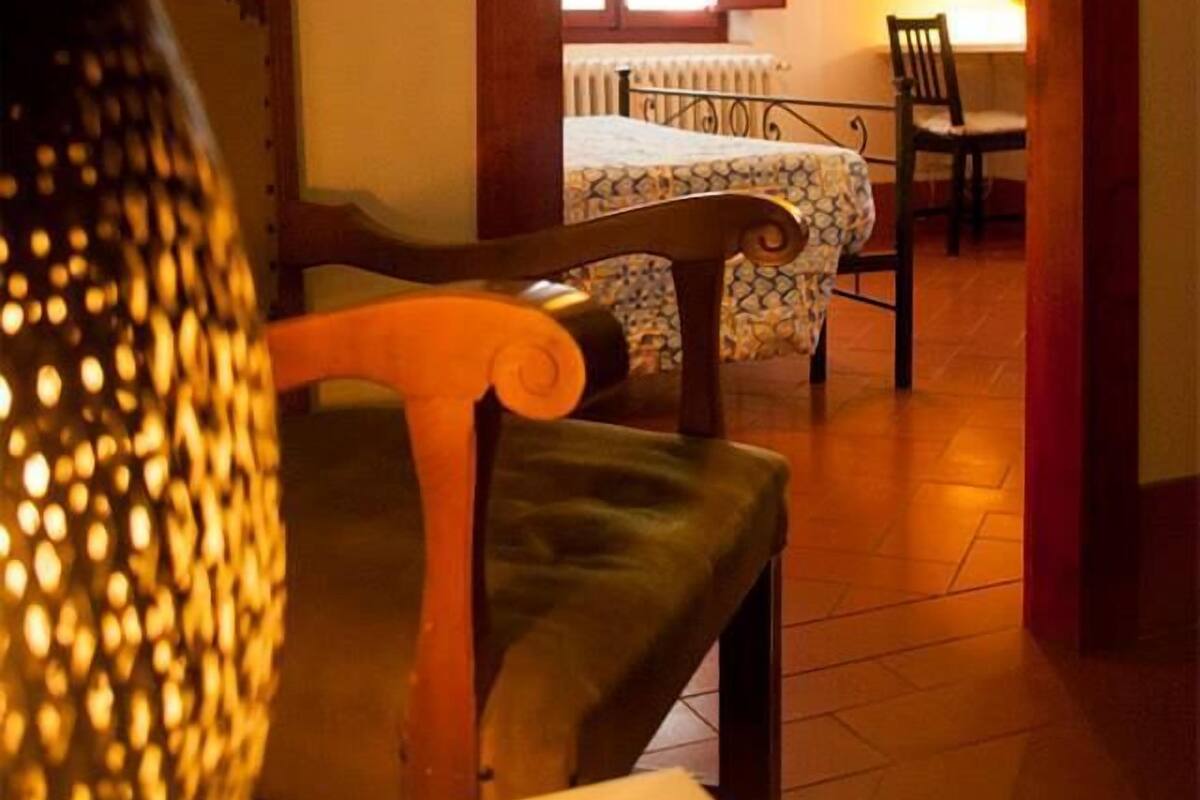 A cozy room with a wooden ceiling, a dining table with chairs, and a bed with a patterned bedspread.