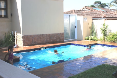 Una piscina al aire libre, sillones reclinables de piscina