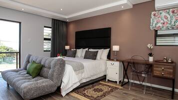 Un dormitorio moderno con una cama grande, un sofá, un escritorio y vistas al exterior.
