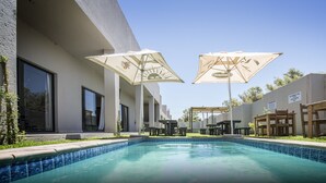 A swimming pool with two umbrellas, outdoor seating, and a sign indicating the pool is for hotel guests only. - Pofadder Inn by Country Hotels (Khâi-Ma)