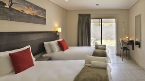 A hotel room with two beds, a desk, a chair, a lamp, and a painting on the wall. - Pofadder Inn by Country Hotels (Khâi-Ma)