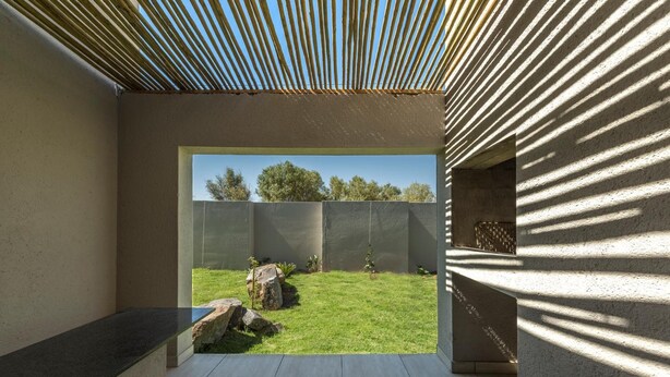 A modern interior with a view of a grassy outdoor area, a concrete bench, and a patterned wall. - Pofadder Inn by Country Hotels (Khâi-Ma)