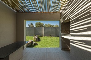 A modern interior with a view of a grassy outdoor area, a concrete bench, and a patterned wall. - Pofadder Inn by Country Hotels (Khâi-Ma)