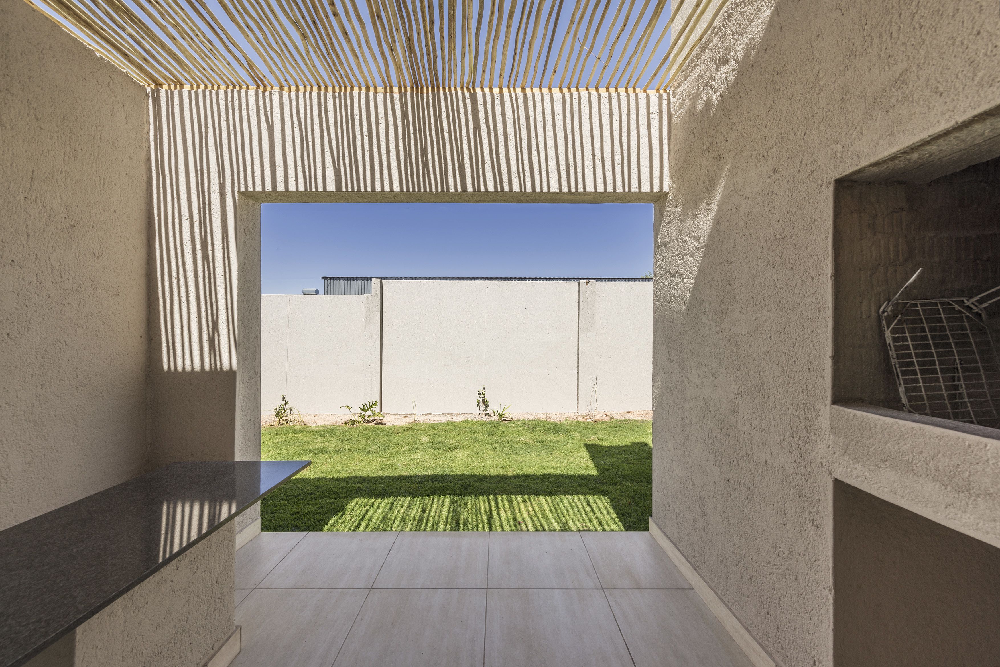 A modern, minimalist interior with a view of a well-maintained lawn and a clear blue sky.