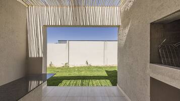 A modern, minimalist interior with a view of a well-maintained lawn and a clear blue sky.