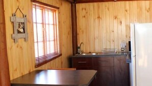 Una cocina compacta con paredes de madera, un lavamanos y un refrigerador.