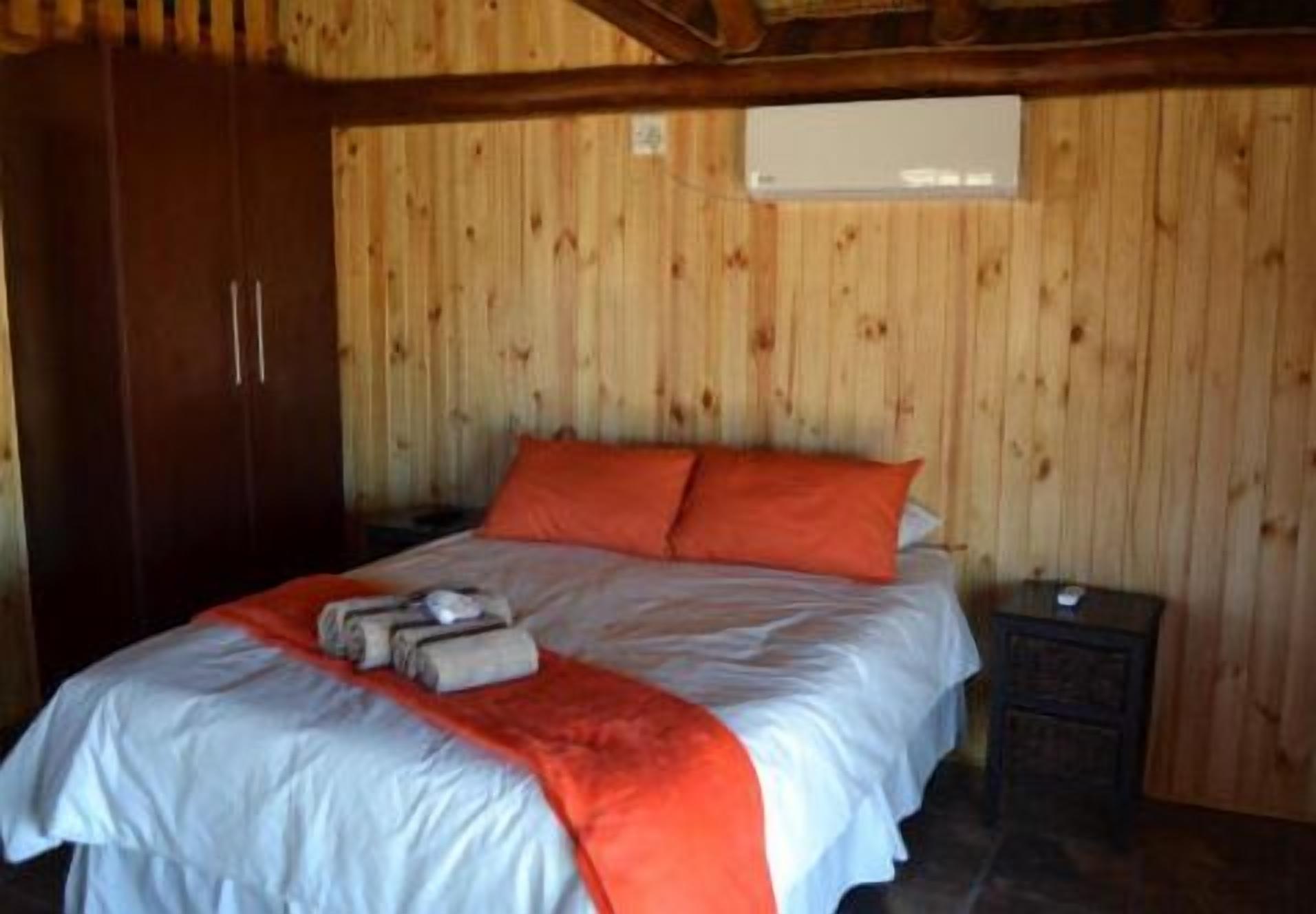 A wooden-paneled room with a bed, a nightstand, and a wardrobe.