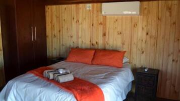 A wooden-paneled room with a bed, a nightstand, and a wardrobe.