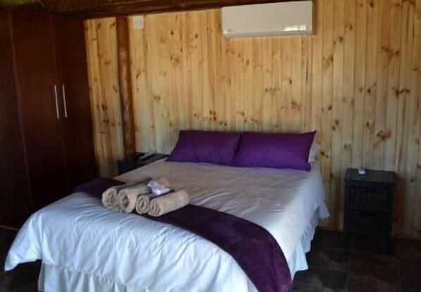 Una habitación con paneles de madera, una cama, un armario y una mesita de noche.
