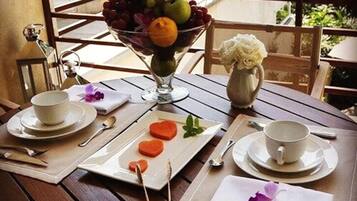 A dining table set with a fruit bowl, plates, cups, and cutlery.