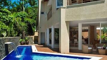 A modern two-story house with a swimming pool, outdoor furniture, and a patio area.