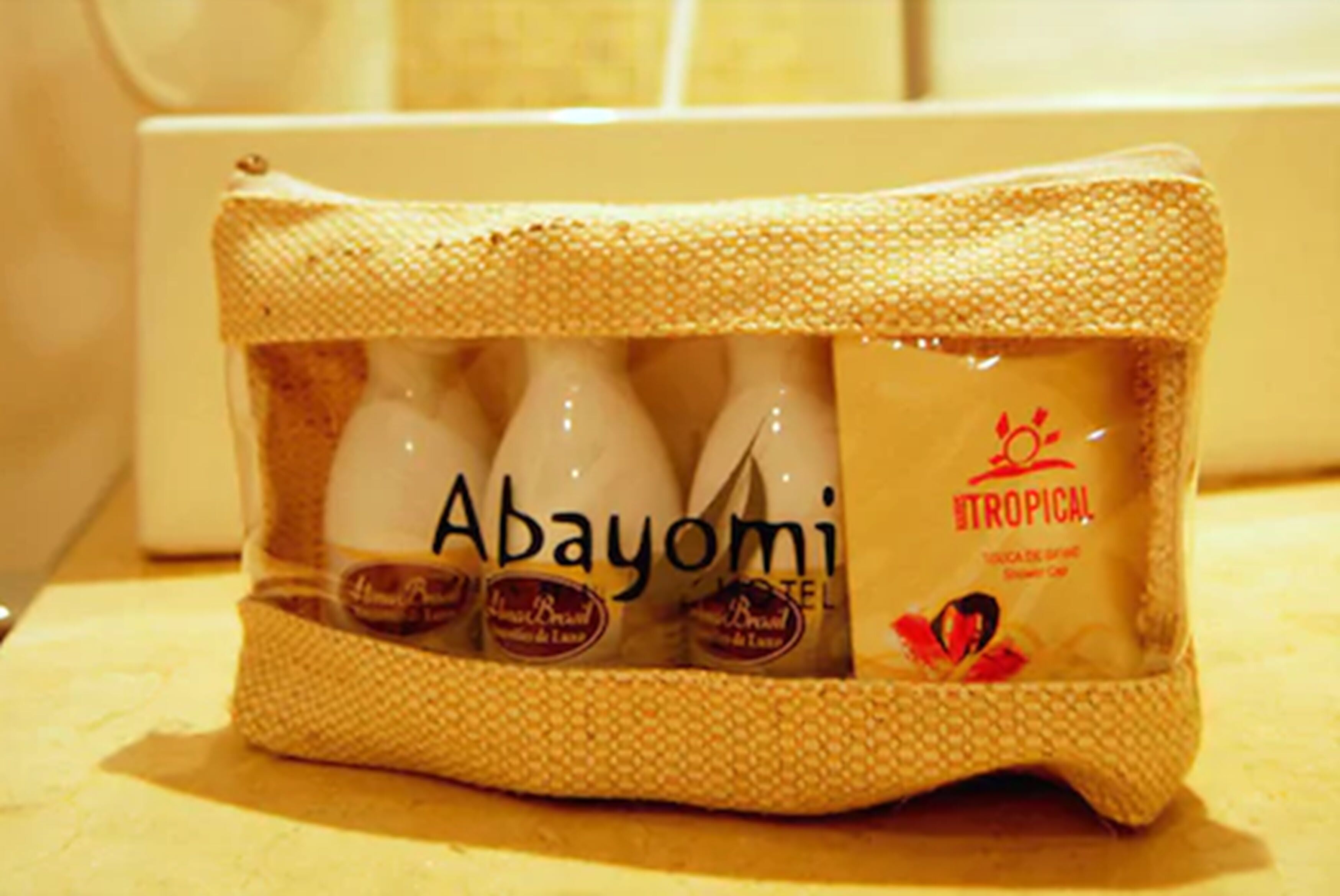 Una bolsa tejida que contiene botellas de gel de ducha Abayomi Tropical.