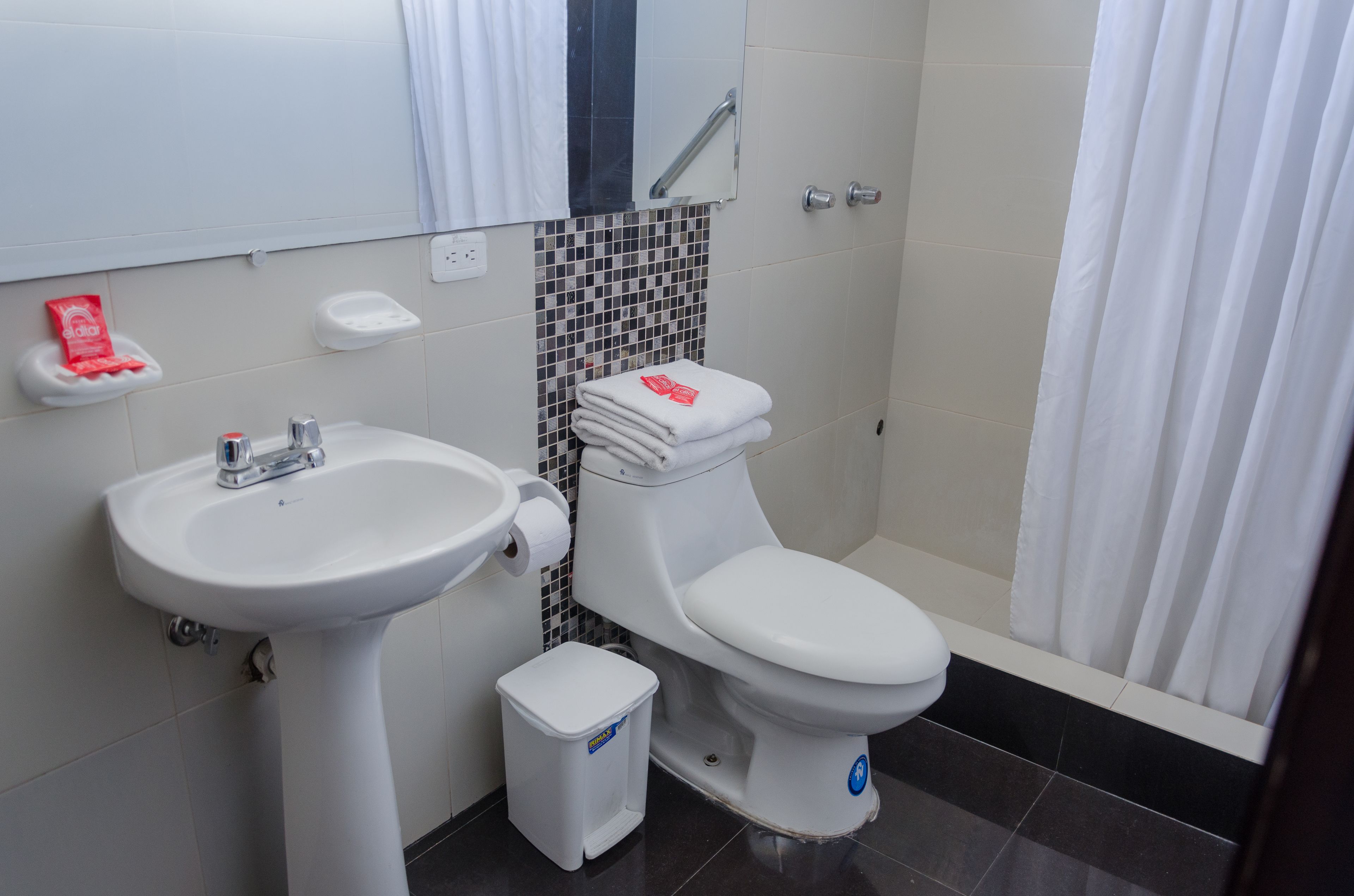 A bathroom with a white sink, toilet, and shower curtain.