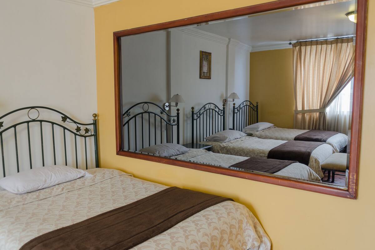 A room with two beds, a large mirror, and a framed picture on the wall.