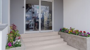 A building entrance with a glass door, steps, and flower planters. - Hotel El Altar (Riobamba)