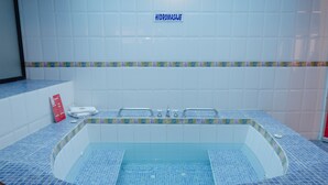 A spa area with a blue-tiled hot tub, a sign reading "HIDROMASAJE," and a red informational card on the left. - Hotel El Altar (Riobamba)